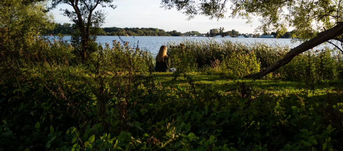 Anneke zit tussen het riet en kijkt uit over het meer