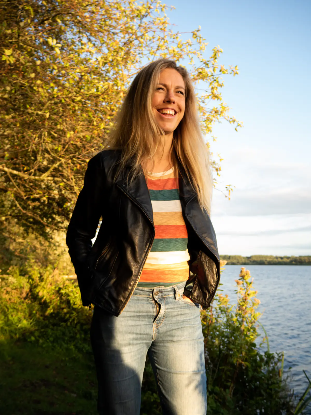 Anneke staat lachend aan het water in het avondlicht