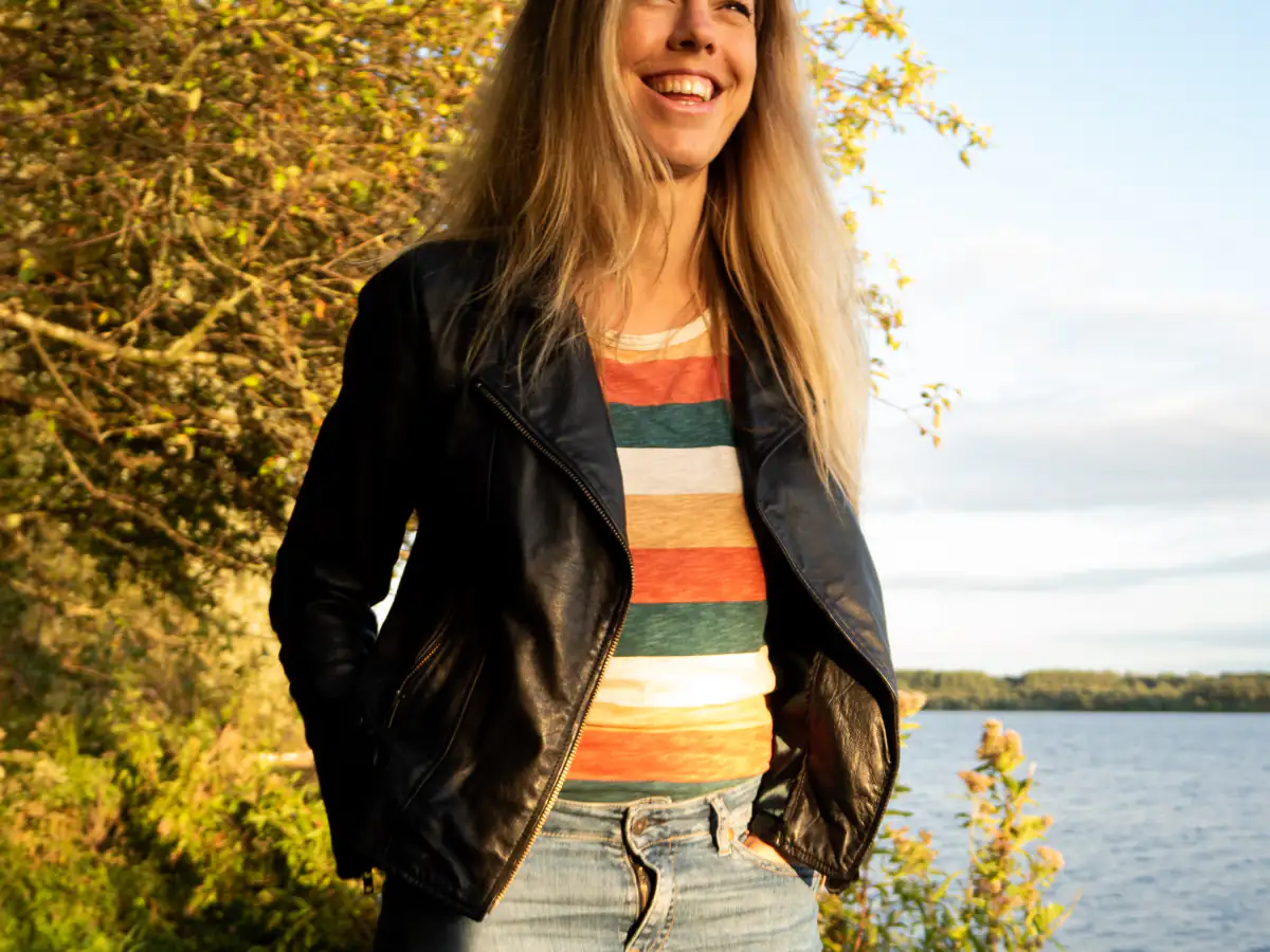 Anneke staat lachend aan het water in het avondlicht